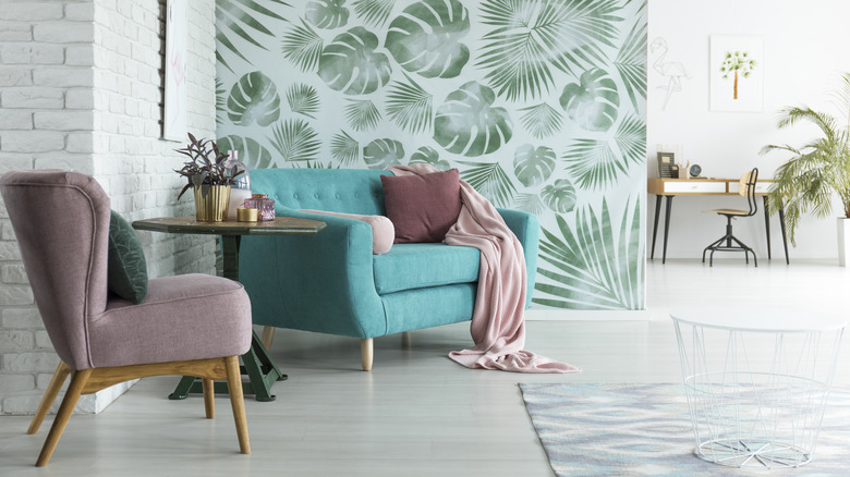 A leaf motif accent wall with pink and teal furniture