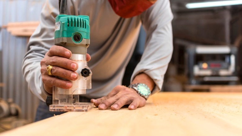 Man using handheld router to add roundover edge to DIY table top