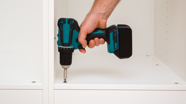 Hand using drill on piece of furniture