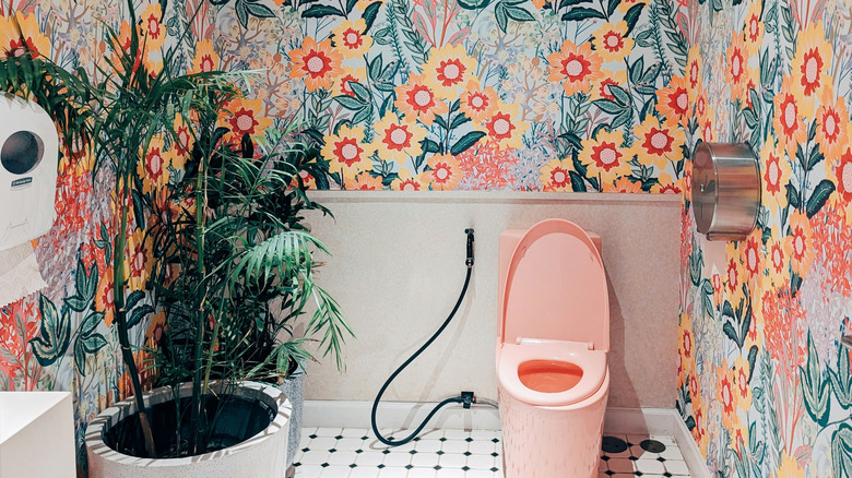 Vibrant bathroom with pink toilet and bold floral wallpaper