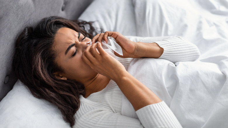 Woman blowing nose in bed
