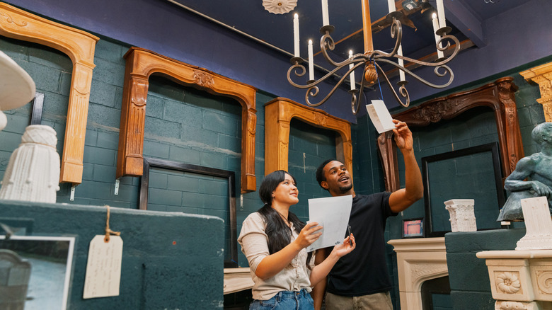 Man and woman looking at antique chandelier in vintage store.