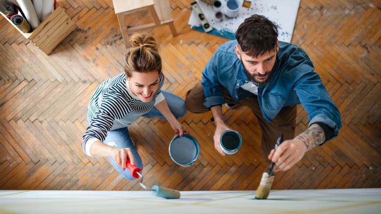 Two people painting wall