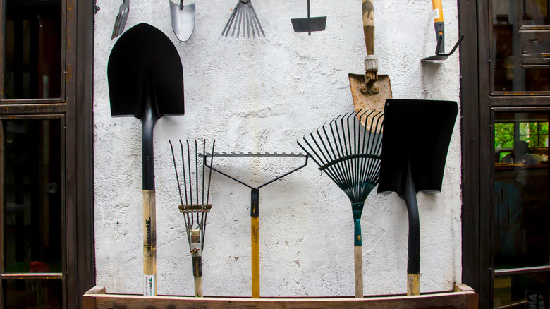 Shovels and rakes stand in a storage system and smaller tools hang from above