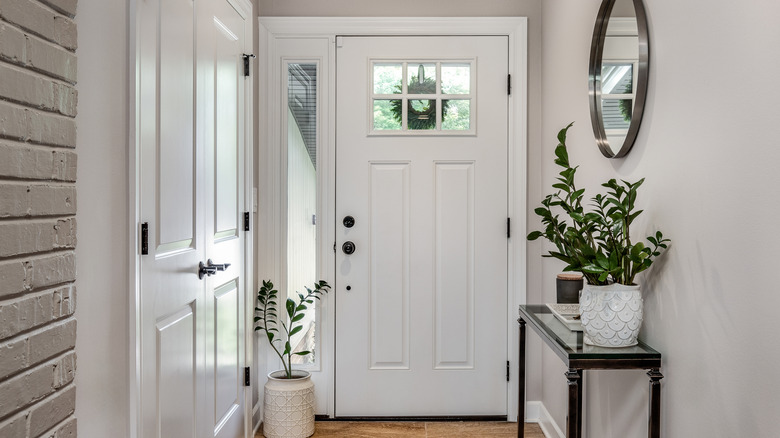A clean, freshened entryway space, with a console table, a mirror and some plants in pots