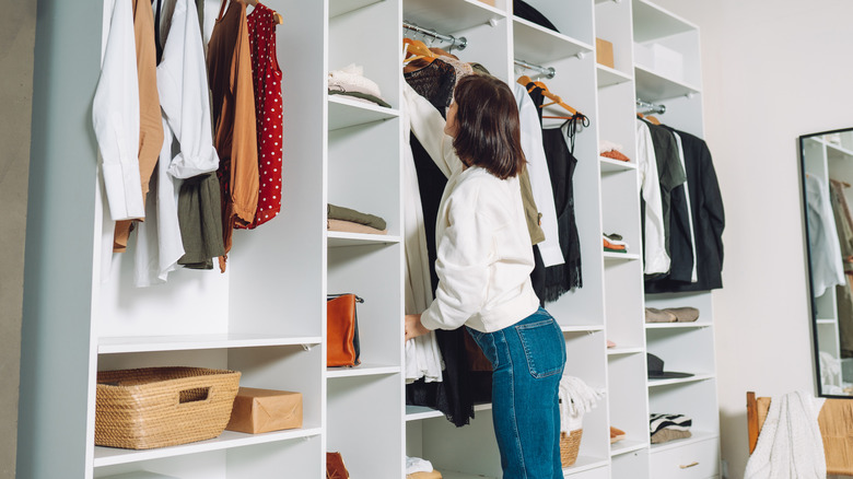 A woman hangs her clothes in the closet