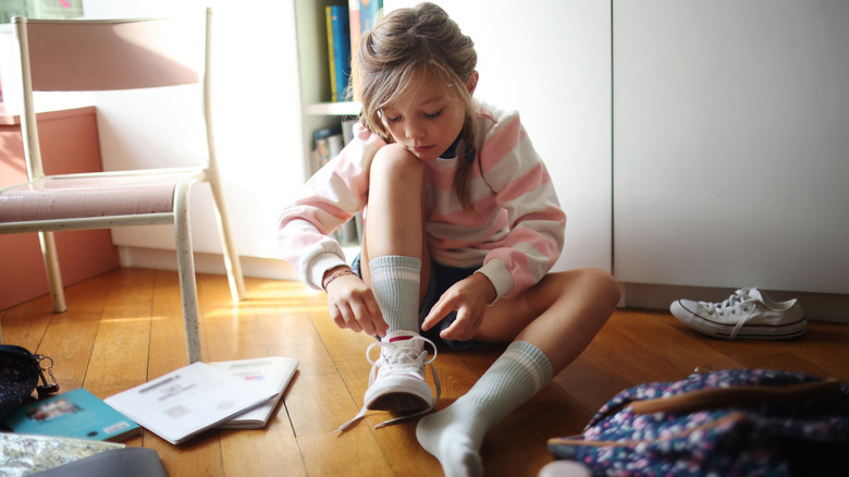 Young girl tying her shoes before school
