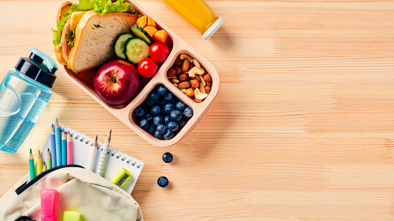 School lunch box next to a backpack and water bottle