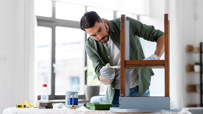 Man painting wooden table blue