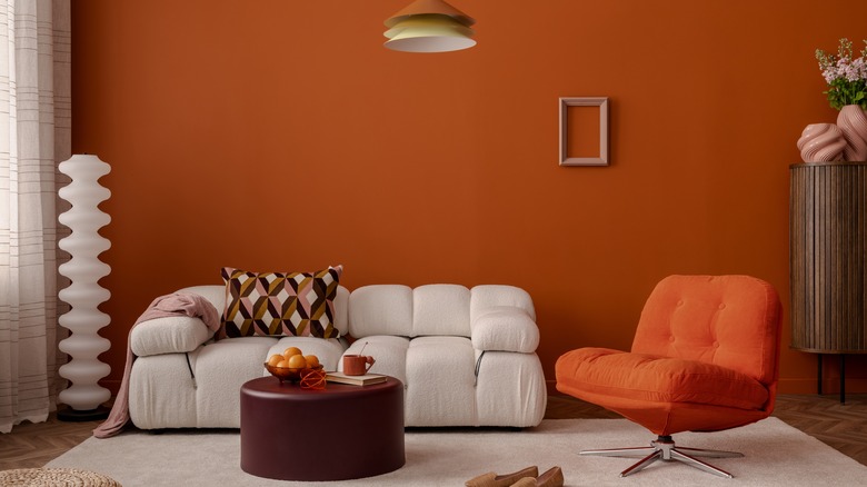 A living room with a burnt orange wall and a white couch