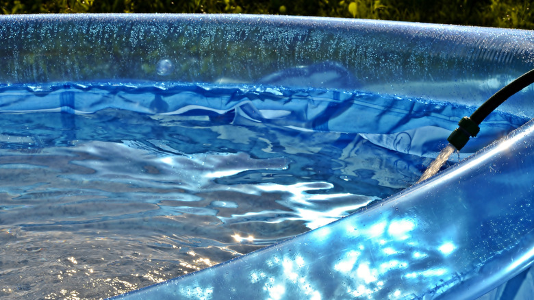 Transparent Inflatable pool being filled with water outdoors