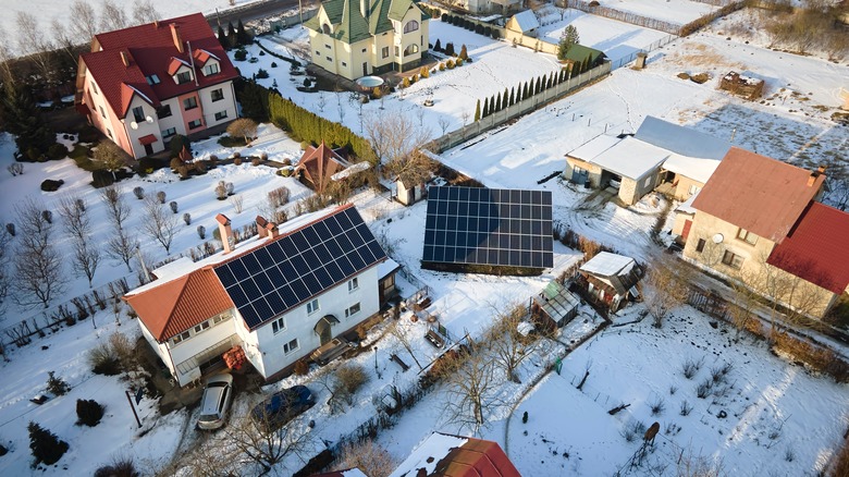 Aerial view of house roof with solar panels covered with snow melting down in winter for producing clean energy