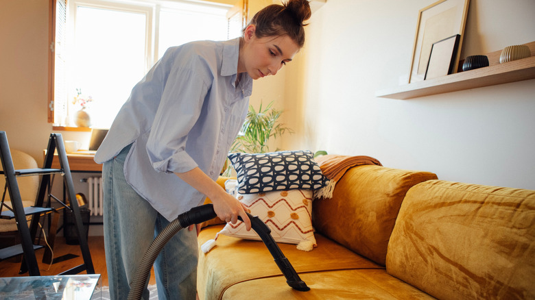 a woman vacuums her couch