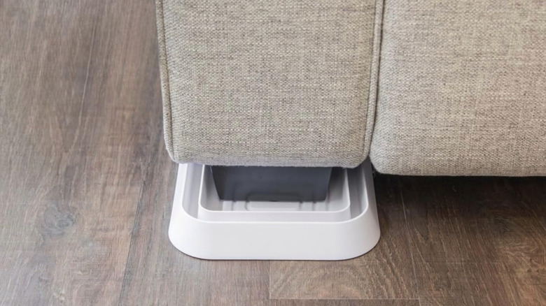 A white bed bug interceptor on the foot of a piece of furniture