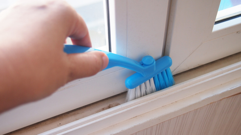 Person cleaning sliding tracks with slim cleaning brush