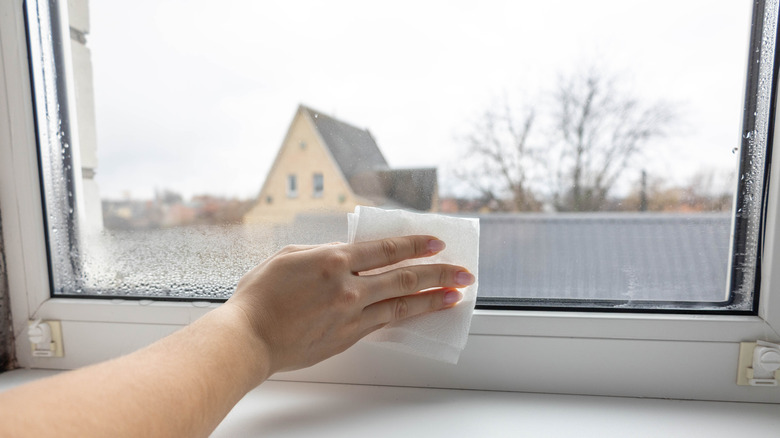 a woman wiping condensation from a glass window