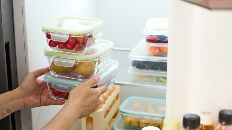 Someone putting containers of produce into a refrigerator