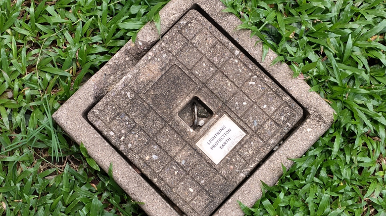 A lightning protection earth pit is installed in grass to provide electrical grounding