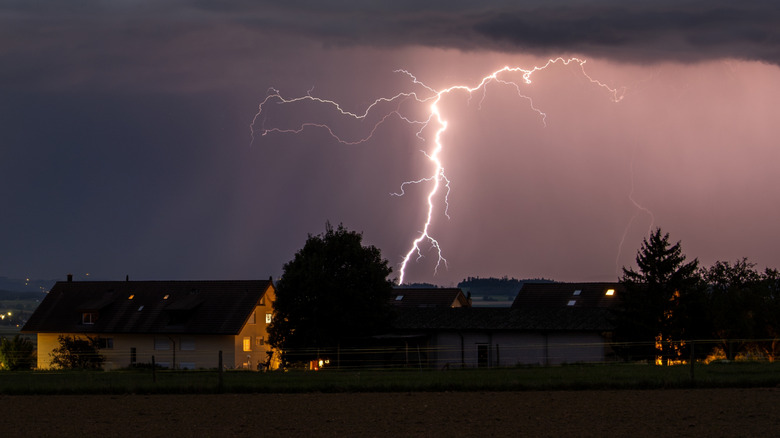 Lighting in the sky behind houses on a stormy night