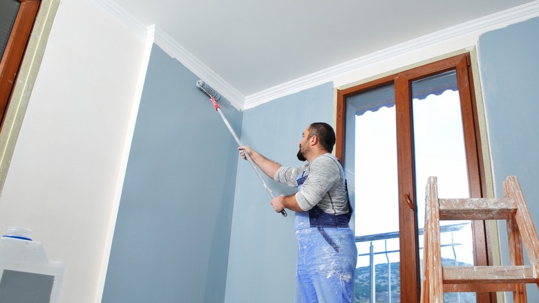 Man painting interior walls blue 