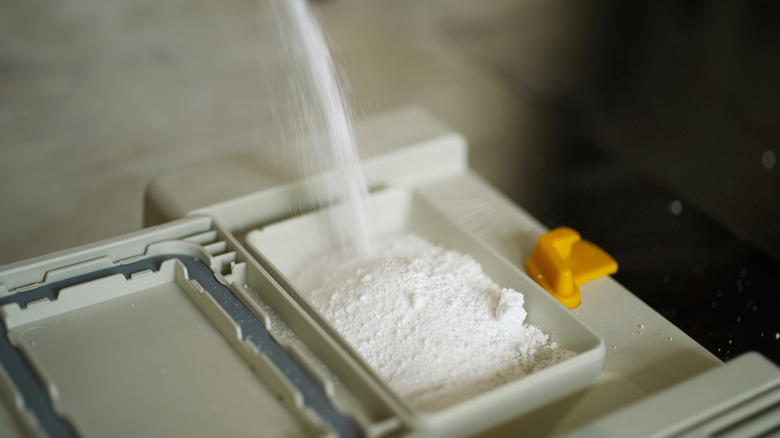 Pouring detergent powder into dishwasher detergent compartment