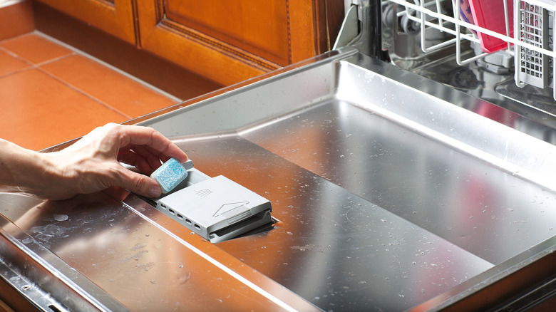 Hand putting dish tab into dirty dishwasher