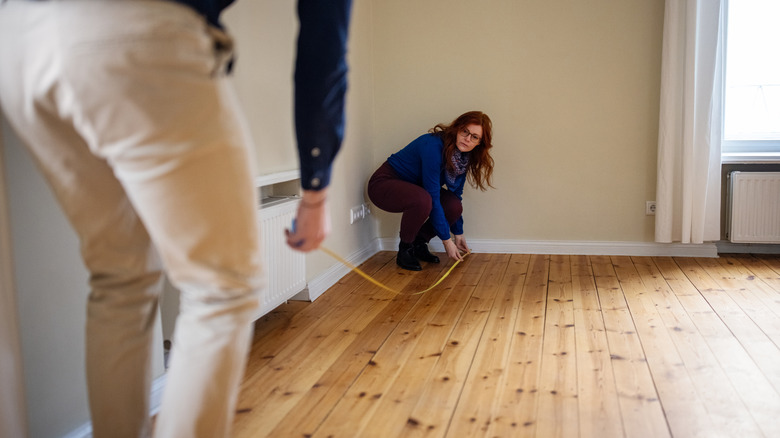 Woman and man measuring a room's length