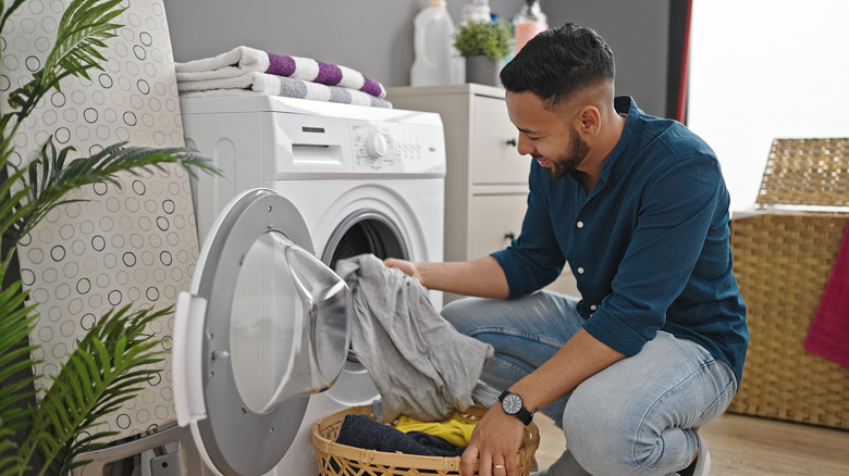 Man removing clean clothes from a washing machine