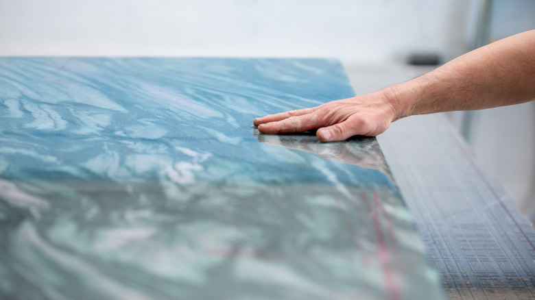 A person's hand placed on a granite countertop