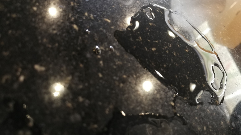 A patch of water on a black granite countertop