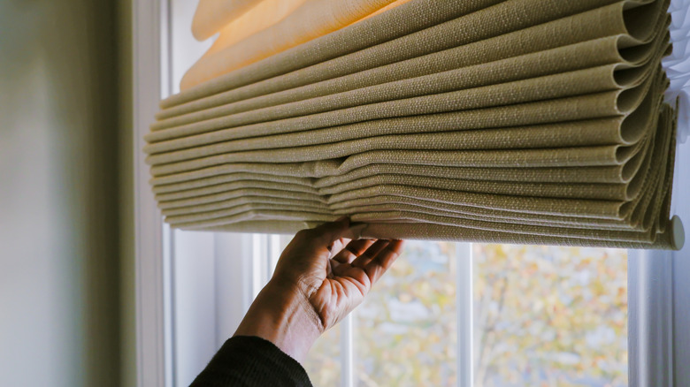 Person adjusting a room shade