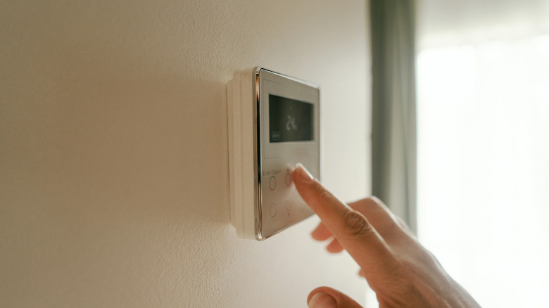 Home air conditioner control panel with a person selecting the temperature and airflow mode.