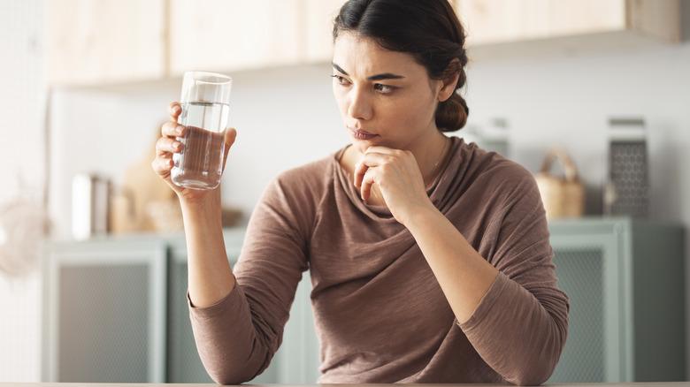Woman looking suspiciously at glass of water