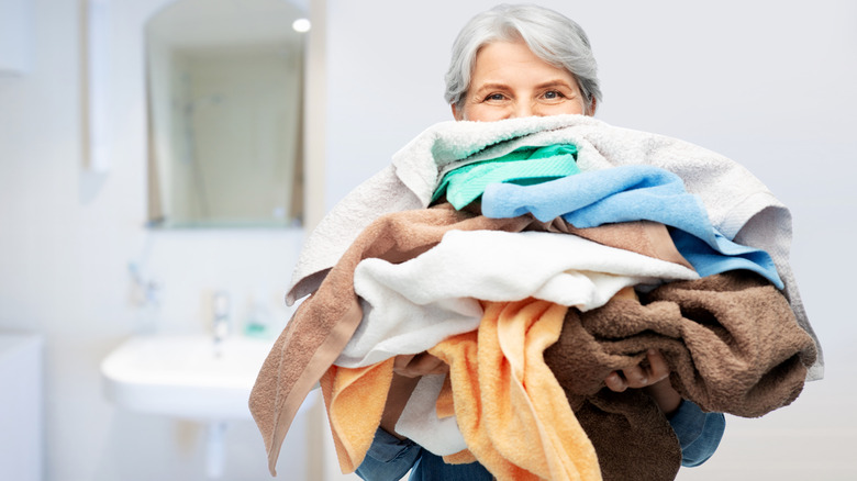 Person carrying stack of towels