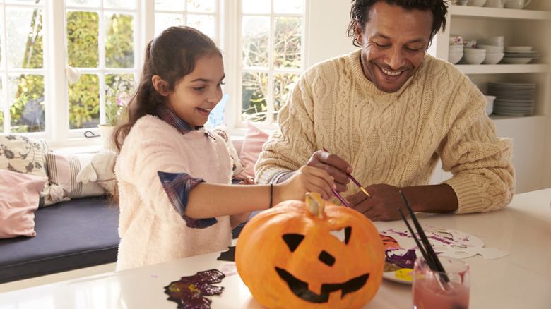 daughter and father painting pumpkin