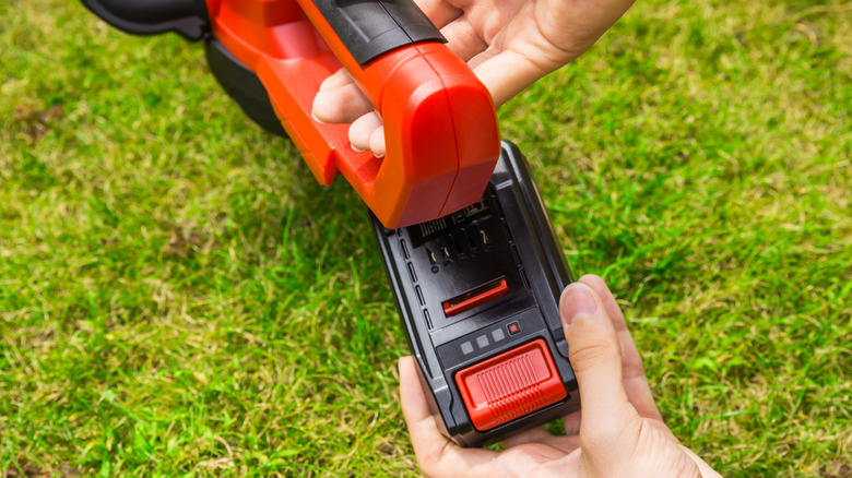 Person detaching battery from lawn tool