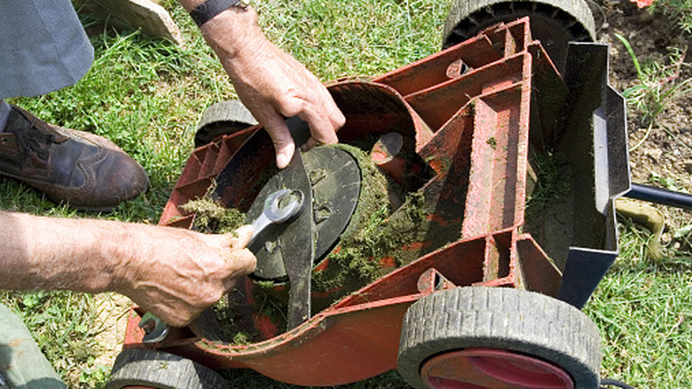 person working on lawn mower blade