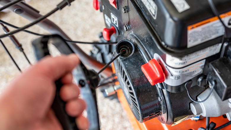 person pulling lawn mower pull starter