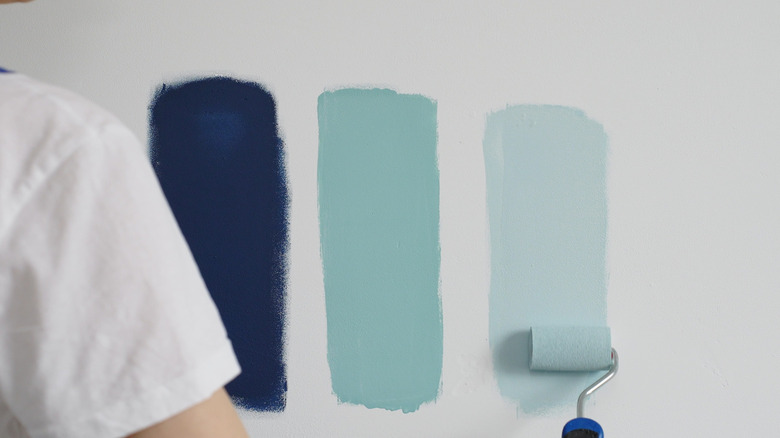 Someone paints blue paint swatches on the wall.