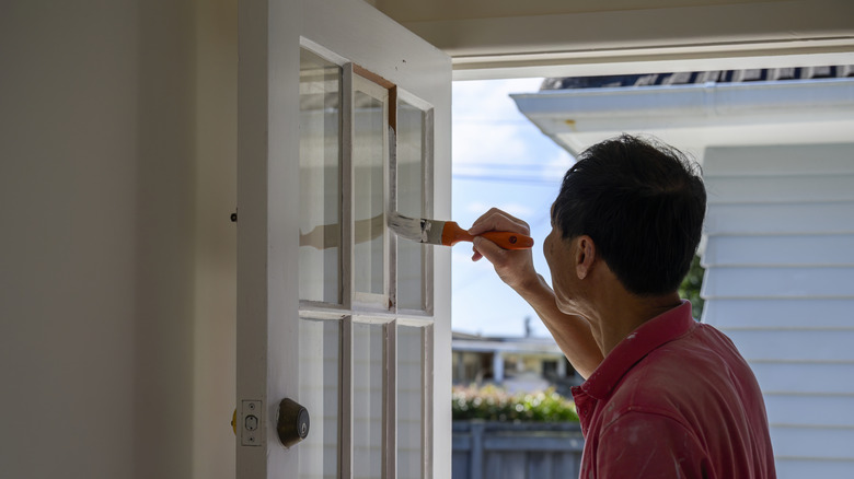 Man painting the front door of a house white