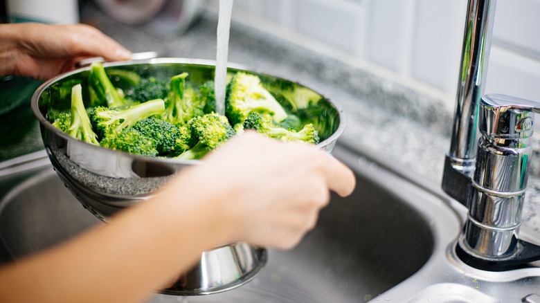 Woman washing broccoli in the kitchen sink