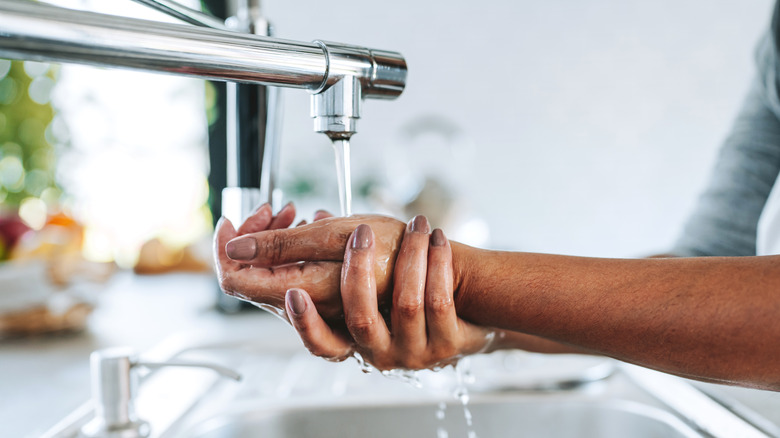 someone washing hands under faucet