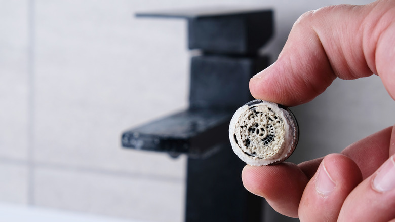 person holding a removed aerator that is full of build up
