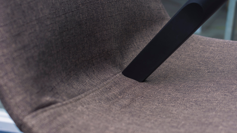 A vacuum nozzle pressed into an upholstered chair