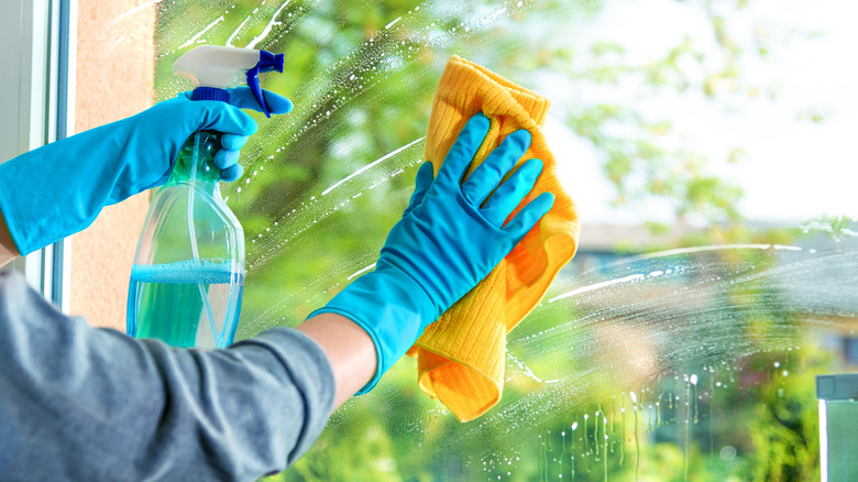 Cleaning a window with microfiber cloth and dish soap solution.
