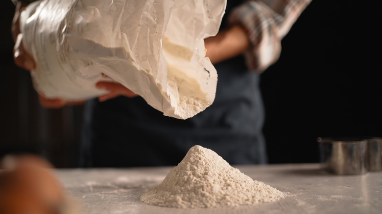 A person pouring flour onto a surface