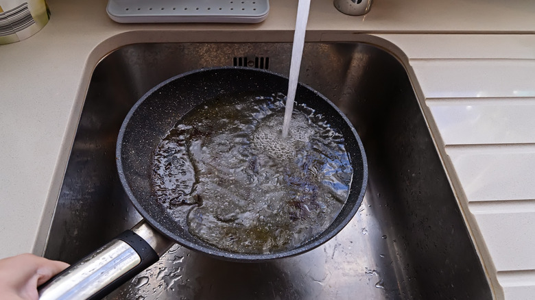A greasy pan under a hot water tap
