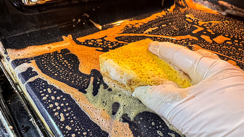 Close-up of a hand cleaning out a greasy oven