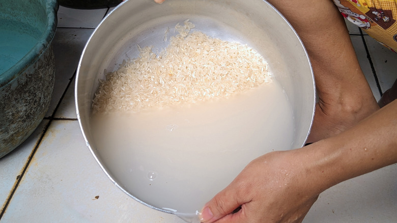 Person rinsing rice in a large bowl