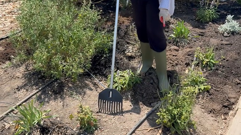 Woman raking dirt off landscape fabric